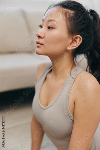 Asian woman at home exercising stretching and yoga on video online looking at laptop and smiling, home workout stretching legs and back dog face up on mat to maintain body health as a lifestyle