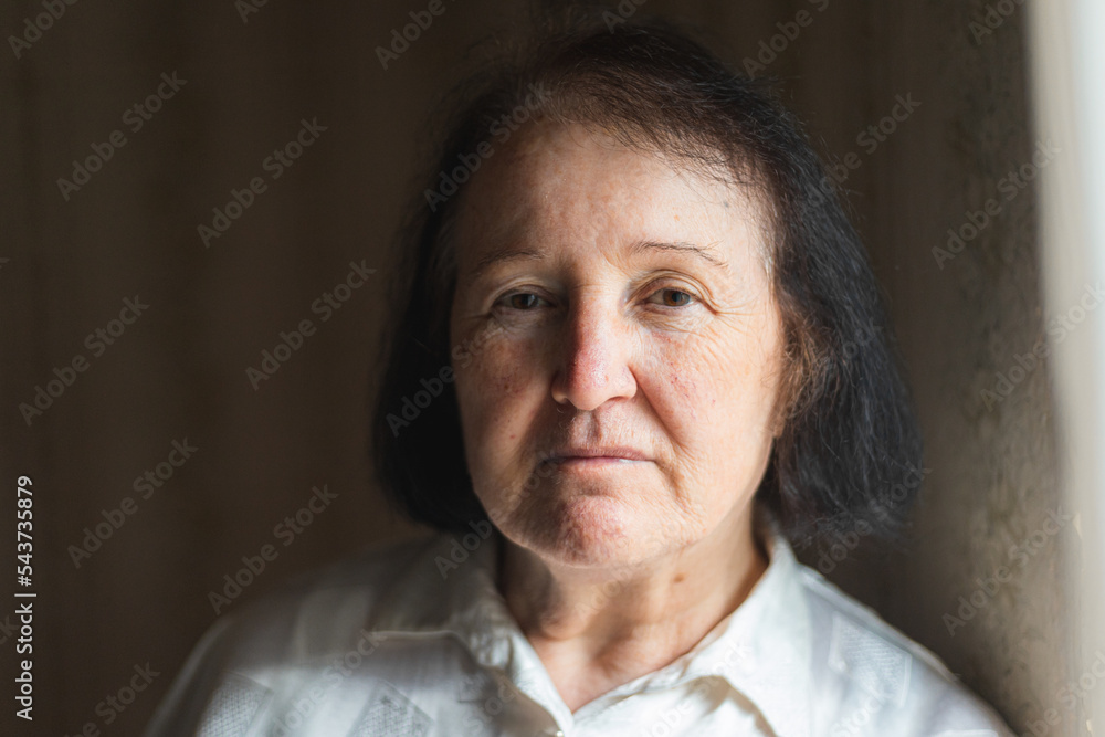 Portrait of an elderly woman standing by the window Portrait of an elderly woman standing by the window