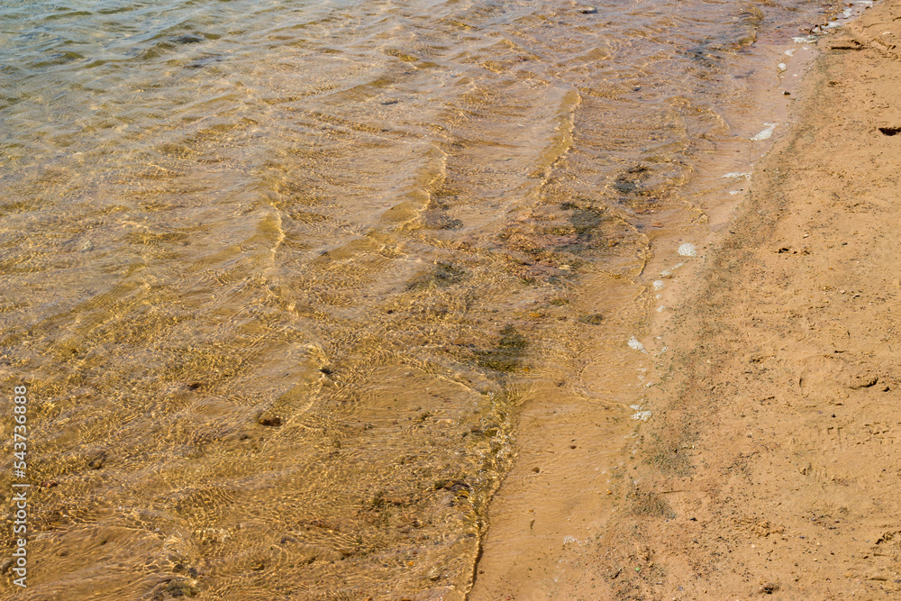 Small waves on the surface of the water on the sandy beach