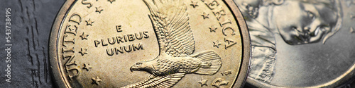 American coins close up lie on dark surface of office table. Soaring eagle Sacagawea dollar coin. Banner or header. News about inflation and Fed rate. USA public debt and treasurys. USD. Macro
