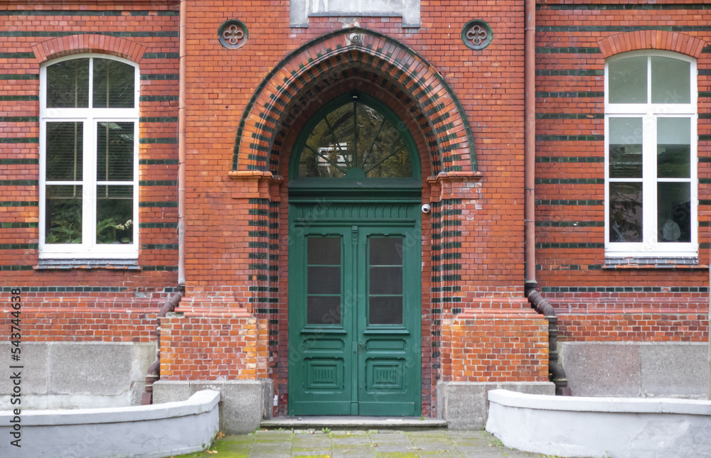 Old green door on a brick wall building with windows