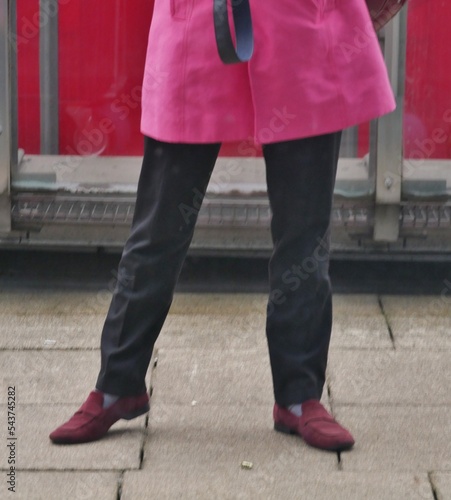 Frau trägt rosa Mantel und steht auf Betonfußboden