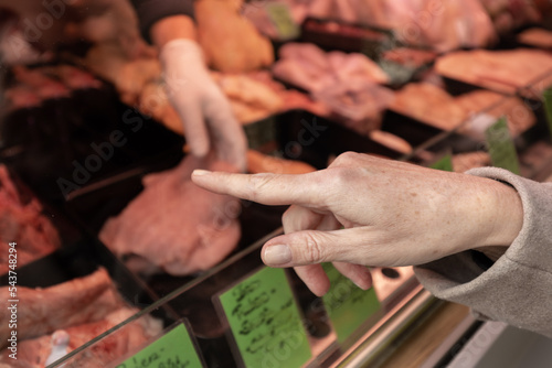 A woman points to an item in a butcher's shop that she wants to buy. Shopping market, Austria, Salzburg © Guzel