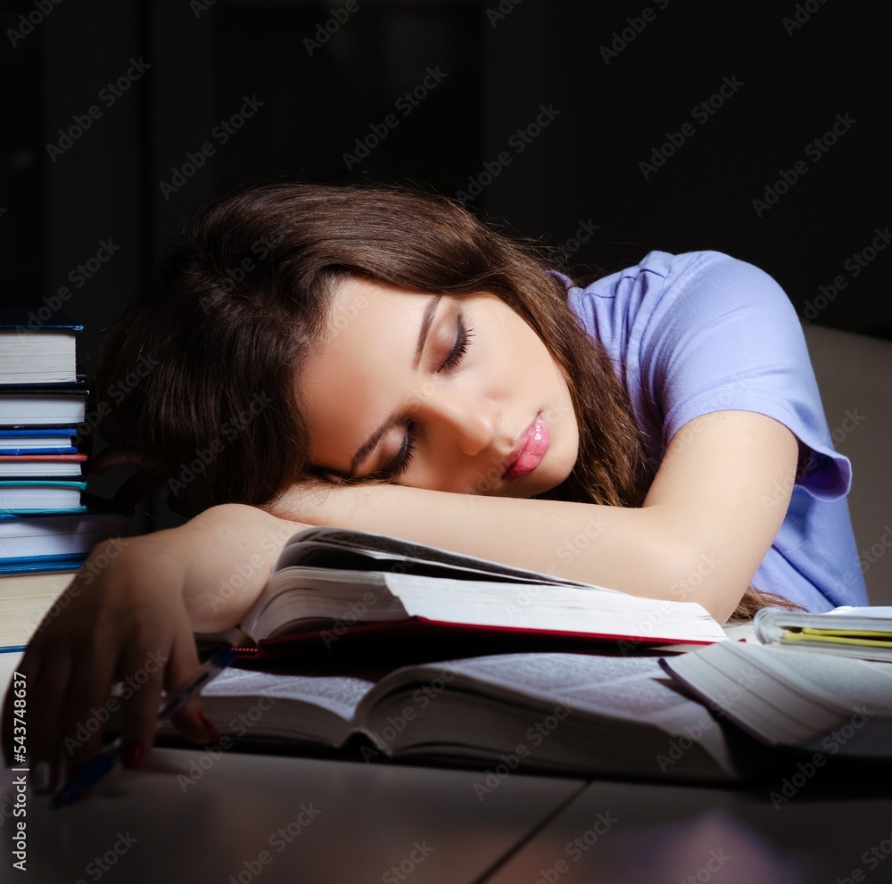 Young female student preparing for exams late at home