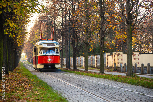 Old vintage tourist tram comes through the alley of a Prague city in an autumn day. Electric transport connection. Prague tram network is third largest in a world. Retro historic electro transport