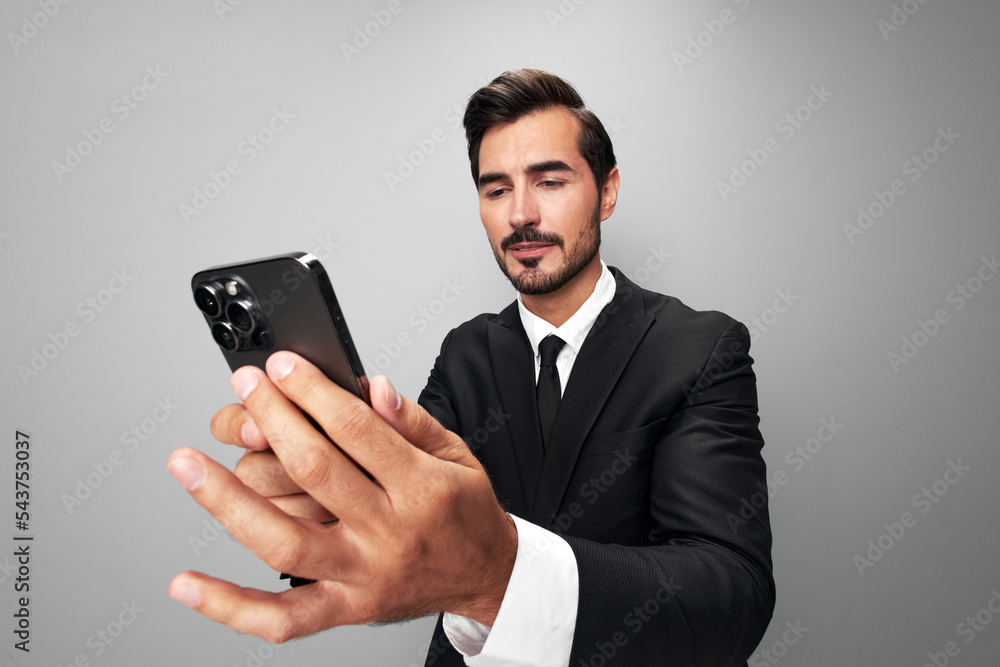 Man businessman holding the phone in his hand looking at him. Headache and anger from failure stress. Close-up wide angle photo gray isolated background Man businessman holding the phone in his hand looking at him. Headache and anger from failure stress. Close-up wide angle photo gray isolated background