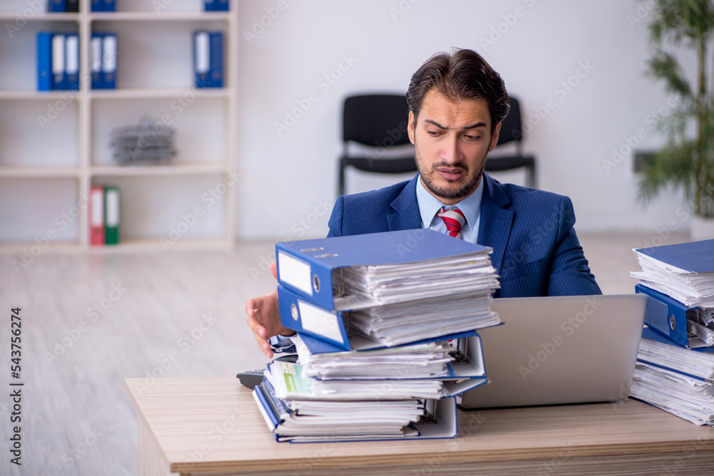 Young male employee and too much work in the office Young male employee and too much work in the office