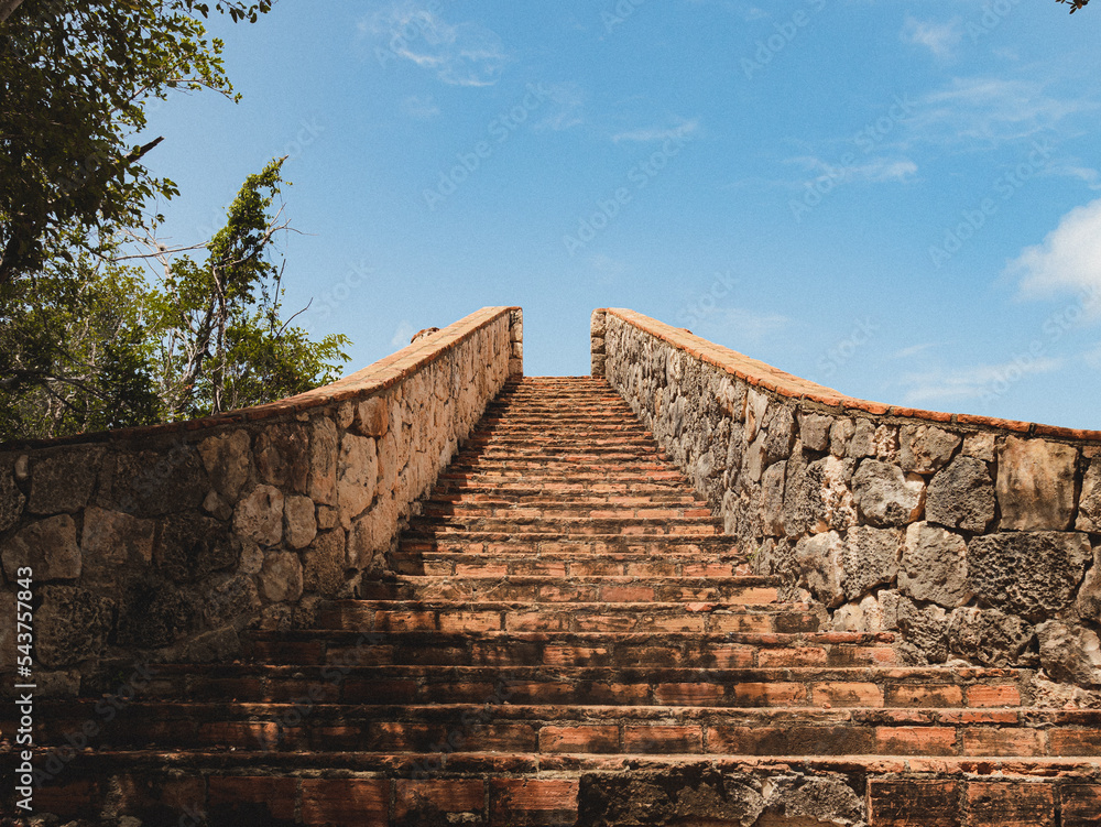 Perspective of a old brick stone stairs pointing to the blue sky from fuerte capron in puerto rico 