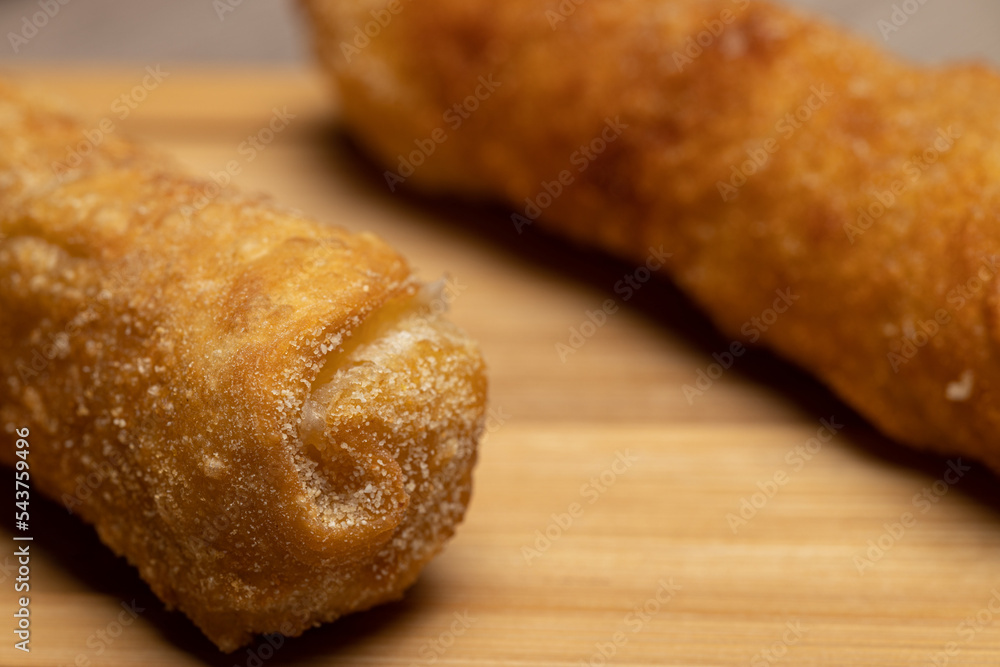 closeup photo of some guacamole sauce and two breaded cheese rolls or tequeños closeup photo of some guacamole sauce and two breaded cheese rolls or tequeños