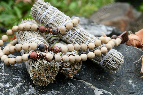 A close up image of three healing smudge sticks with wooden mala beads. photo