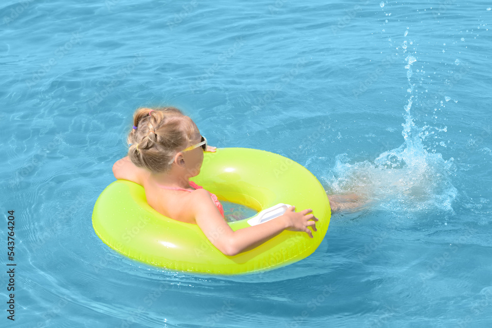 Little girl with inflatable ring in sea on sunny day