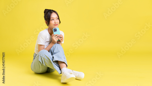 portrait of a beautiful young asian girl sitting on a yellow background photo