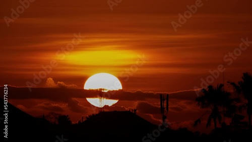 Wallpaper Mural big sun timelapse and cloudless sky sunset over the rooftops of typical Balinese city houses, location Bali Indonesia, end of the hot summer day Torontodigital.ca