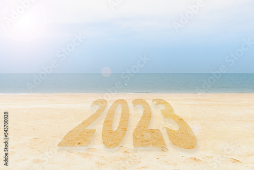 New Year 2023 Concept. inscription is a 2023 number on sand beach. Sandy beach and sea wave beautiful background. Write letters by hand on the beach. change new year of 2023 on sand of beach