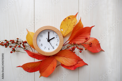 Fall time change still life with colorful  tree foliage and wooden frame clock. Fall back concept background.  photo