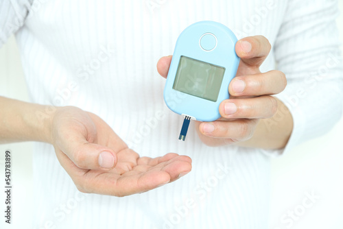 Human hand checking blood sugar with digital tear meter diabetes health check Health and medical concepts.
