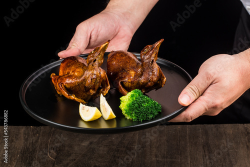 Traditional Cantonese roast pigeon on a and white porcelain plate