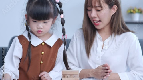 Creative game, imagination child and toy. Cute mum and her child playing with wooden block bricks toy. Happy loving family asia mother and daughter together in modern living room playing with construc photo