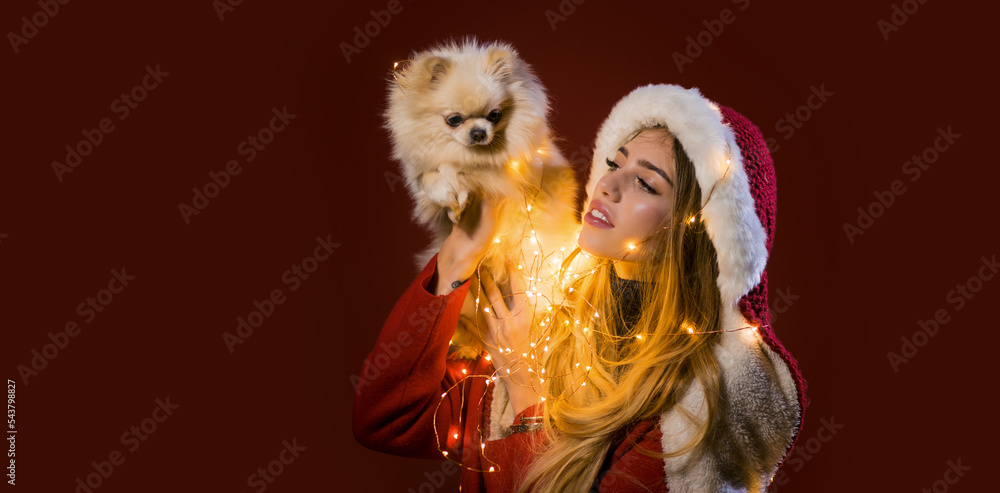 Portrait of a young woman celebrate winter Christmas holidays hold puppy dog on red background.