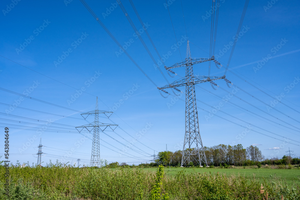 Electricity pylons and power lines in front of a blue sky seen in Germany Electricity pylons and power lines in front of a blue sky seen in Germany