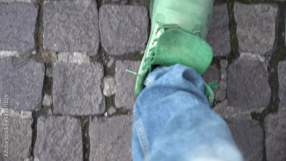 Close up shot of man's lags walking on the pavement street wearing green shoes and jeans. Close up shot of man's lags walking on the pavement street wearing green shoes and jeans.