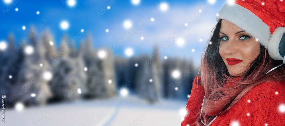 smiling young woman in christmas hat and headphones on snowy background