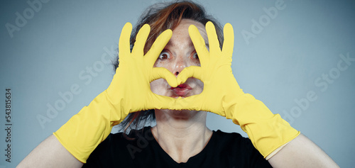 View through yellow gloves on woman portrait. A woman in a black t-shirt. Woman cleaning. Vintage style