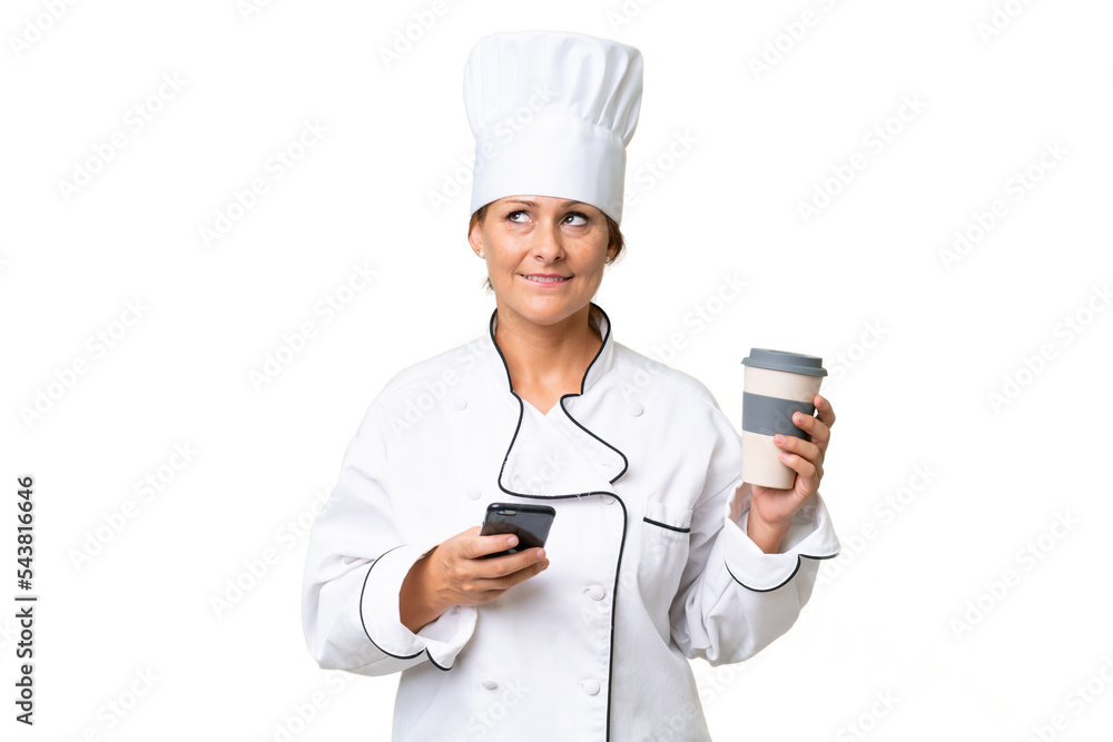 Middle-aged chef woman over isolated background holding coffee to take away and a mobile while thinking something Middle-aged chef woman over isolated background holding coffee to take away and a mobile while thinking something