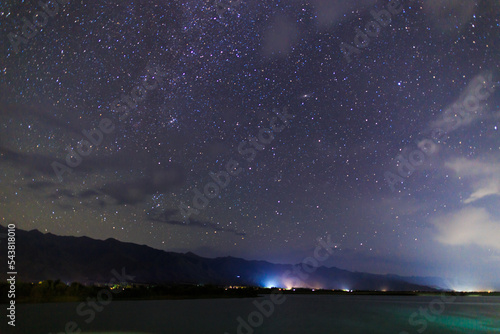 Starry sky on the lake. Night landscape. Sky with clouds. Kyrgyzstan, Lake Issyk-Kul.
