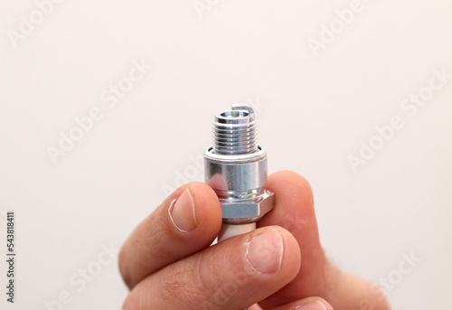 Close up mechanic man holding new automotive Spark plug with single side electrode for car or motorbike maintenance concept.