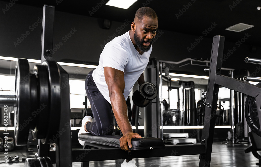 Fit and muscular african man trains with dumbbells. Fit and muscular african man trains with dumbbells.
