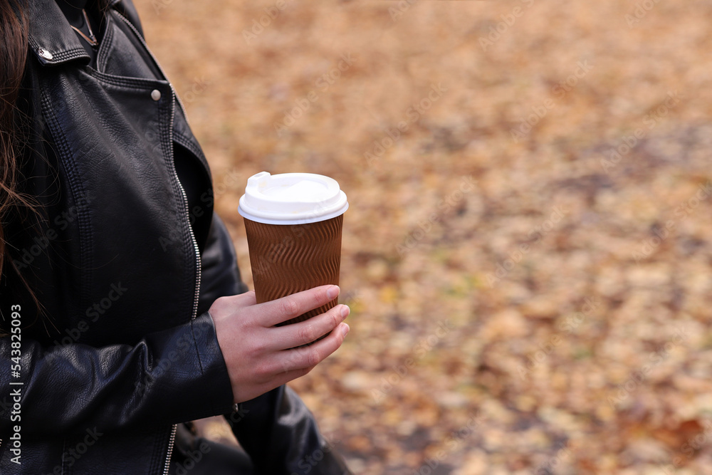 Girl holding a glass of coffee against the background of yellow autumn leaves Girl holding a glass of coffee against the background of yellow autumn leaves