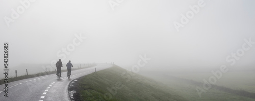 Foto couple on bicycle rides in mist on dike near river rhine in holland