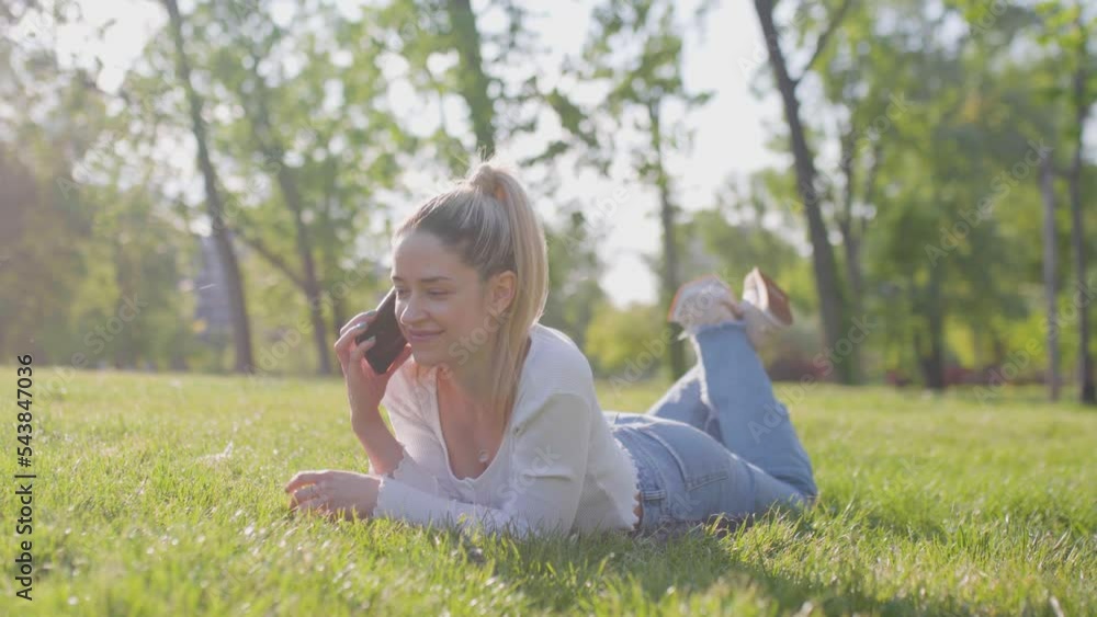 Beautiful girl lying in a field in the park. Talking on phone. Beautiful girl lying in a field in the park. Talking on phone.