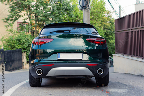 Rear view of a parked modern green SUV in a residential area with a blank European license plate