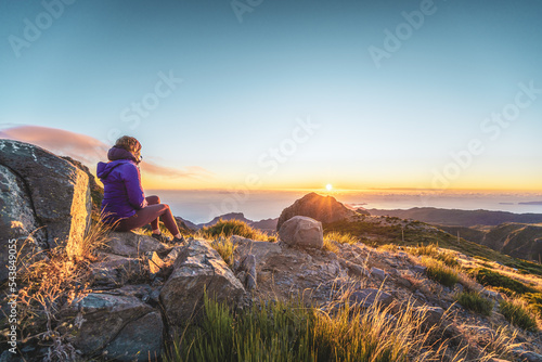 Sitting woman watching the sunrise over the beautiful mountain landscape of Pico do Ariero. Pico do Arieiro, Madeira Island, Portugal, Europe. photo