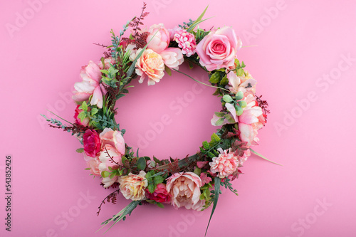 Colorful artificial flowers wreath isolated on pink background.
