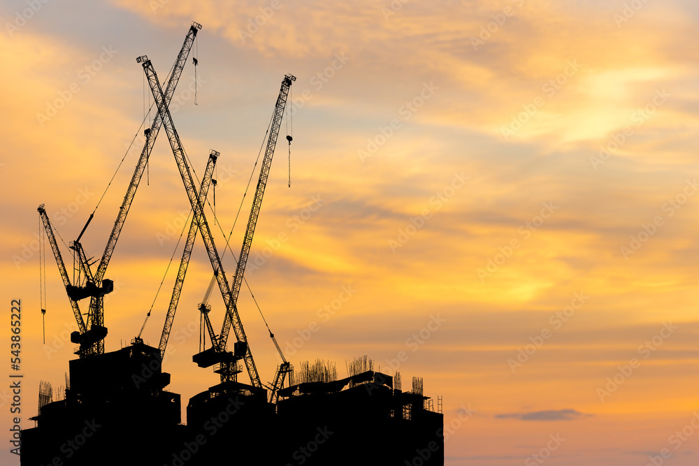 Silhouettes of building construction site and construction cranes with clipping path sunset background