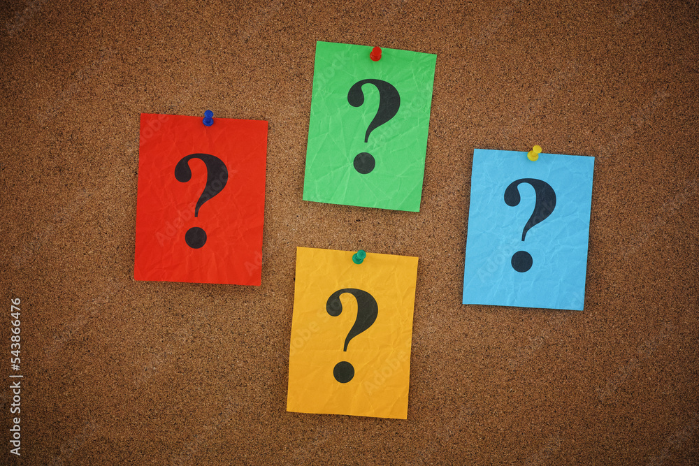 Colorful crumpled paper notes with question marks on them pinned to a cork board Colorful crumpled paper notes with question marks on them pinned to a cork board