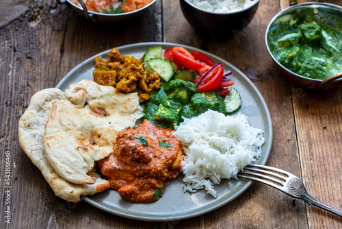 Butter chicken, saag paneer, toamto salad and naan bread photo