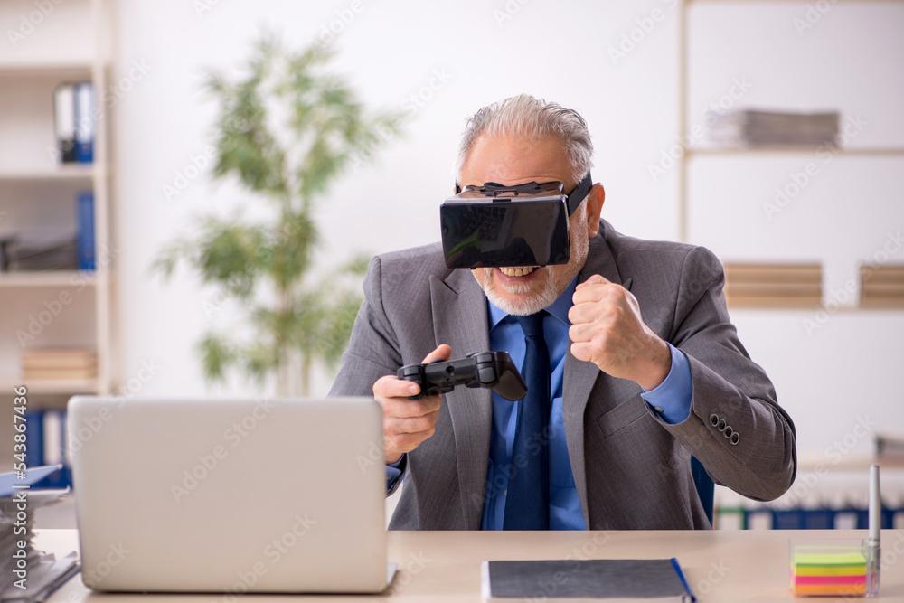 Old male employee enjoying virtual glasses at workplace Old male employee enjoying virtual glasses at workplace