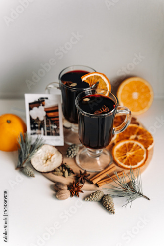 Composition of glasses with mulled wine. Spices for mulled wine (anise, cloves, cinnamon, cardamom, nutmeg). Dried oranges and pine needles for decoration. Homemade Christmas coziness and atmosphere.