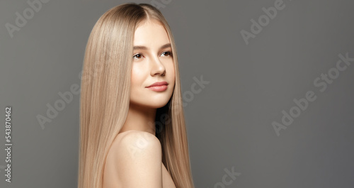 Hair care model.Beauty young woman with long healthy hair posing against grey background. Beauty salon concept