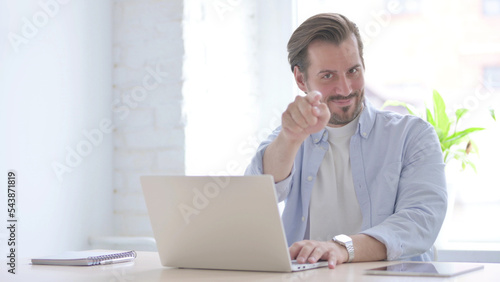 Valokuva Young Man Pointing at Camera while using Laptop