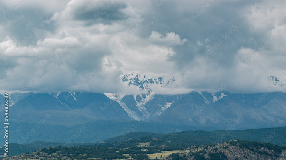 Atmospheric view of snow covered mountain ranges in gloomy clouds