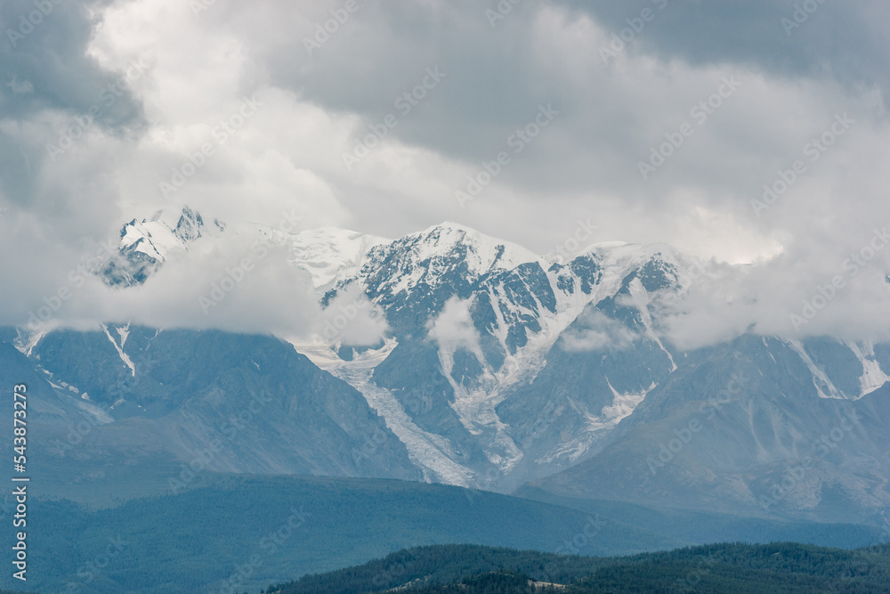 Atmospheric view of snow covered mountain ranges in gloomy clouds