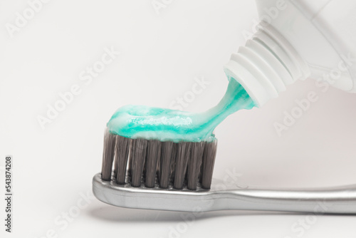 Close up of squeezing toothpaste on toothbrush on white background.