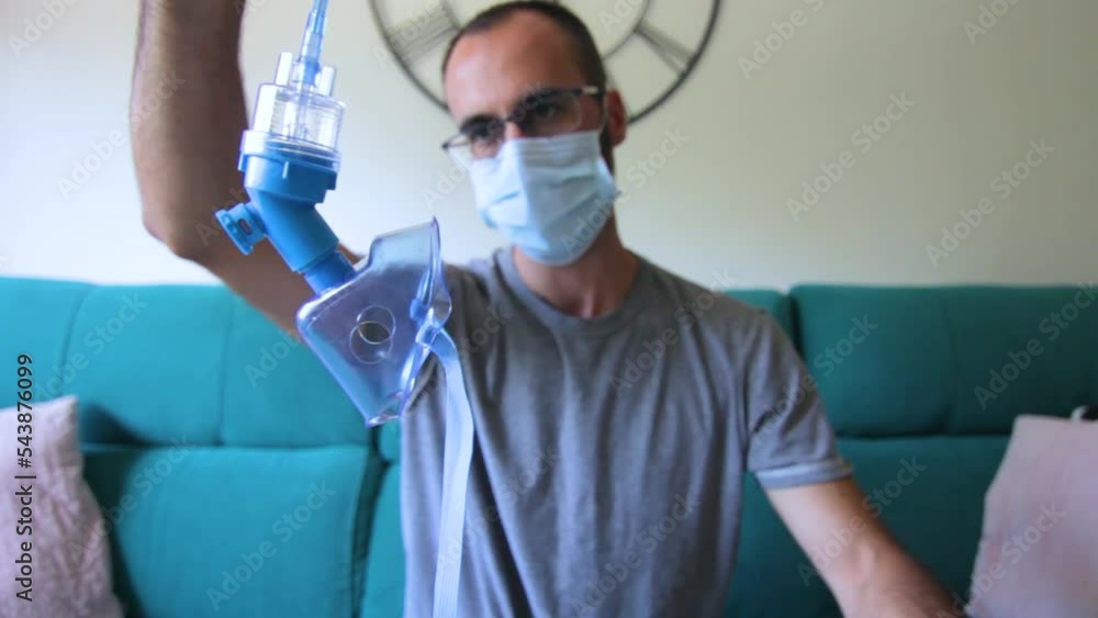 Man with face mask looking at nebulizer Man with face mask looking at nebulizer