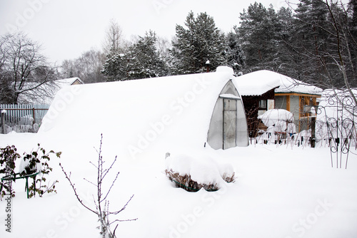 suburban area with a greenhouse under the snow in winter