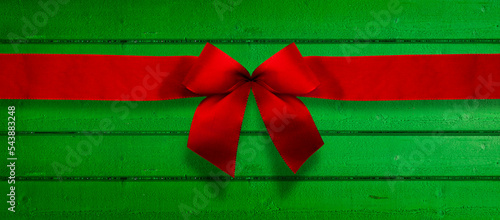 Rote Weihnachtsscheife auf einer grünen Holzwand